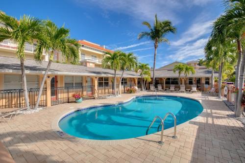 a swimming pool in front of a building with palm trees at Enjoy the Pool while being Steps from Beach and Restaurants! - Coconut Villa's Suite 6 in St. Pete Beach
