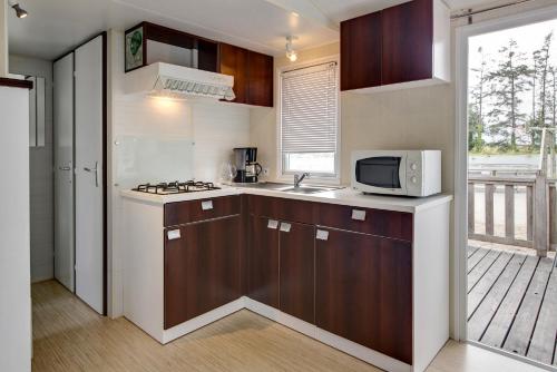 uma pequena cozinha com um micro-ondas e um fogão em Camping Domaine de la Ville Huchet em Saint Malo