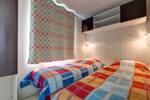 a bedroom with two beds and a window at Camping Domaine de la Ville Huchet in Saint Malo