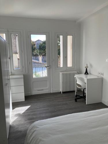 um quarto branco com uma cama, uma secretária e janelas em Coliving salle de sport vidéprojection proxi gare em Agen