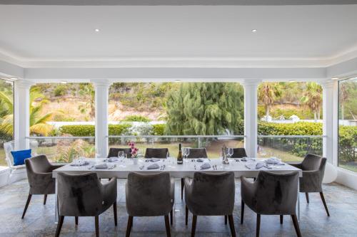 comedor con mesa y sillas y ventana grande en 5 BR Luxurious Beachfront Villa with utmost privacy, en Les Terres Basses