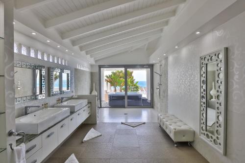 Baño blanco con 2 lavabos y espejo grande en 5 BR Luxurious Beachfront Villa with utmost privacy, en Les Terres Basses