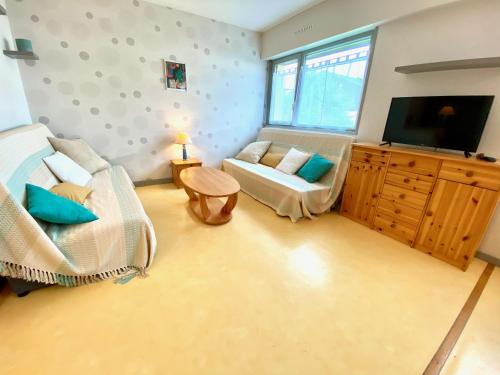 a living room with a couch and a flat screen tv at Taphao, Studio pour 4 avec parking proche mer in Courseulles-sur-Mer