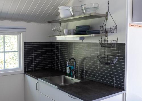 a kitchen with a sink and black tiled wall at Västervik Resort in Västervik