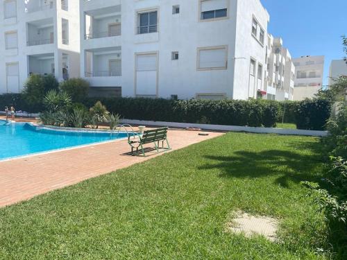 un banc installé dans l'herbe à côté d'une piscine dans l'établissement Apparemment de luxe, à Hammamet