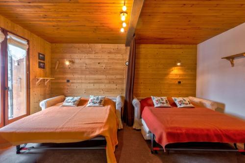 2 camas en una habitación con paredes de madera en Le Bois Joly, en La Giettaz