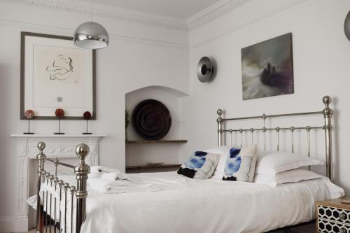 una camera da letto con un letto con lenzuola e cuscini bianchi di Beautiful 4 Bed Beach House a Pevensey