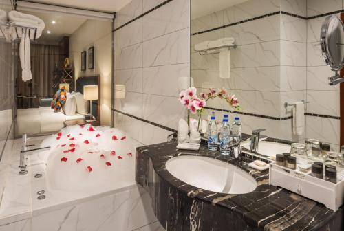 a bathroom with a sink and a tub with red flowers at Alreem Village Hotel in Al Jubail