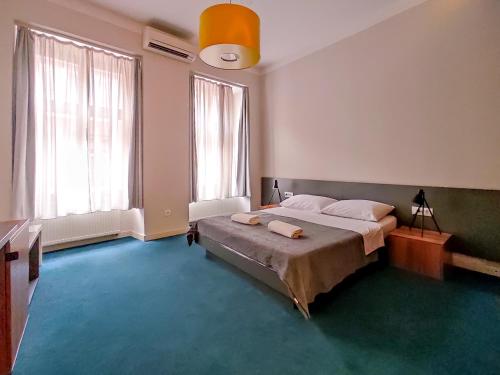 a bedroom with a large bed and two windows at Apartments Cilindar in Zagreb