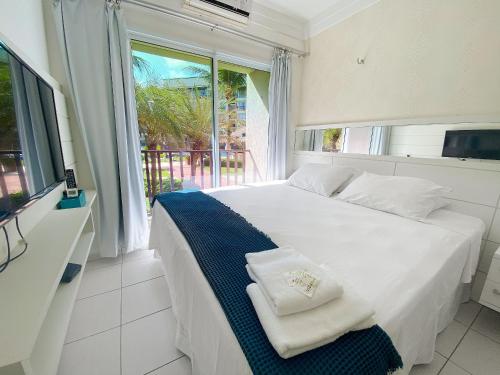 a white bed in a room with a window at Beach Living Pé na Areia por Be My Guest in Aquiraz