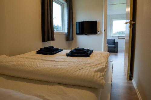 a bedroom with a bed with two black towels on it at Vollvaagen Apartments Smøla, boat included in Smøla