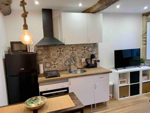 eine Küche mit weißen Schränken und einem schwarzen Kühlschrank in der Unterkunft Bonito apartamento en el centro de Pontedeume. in Puentedeume