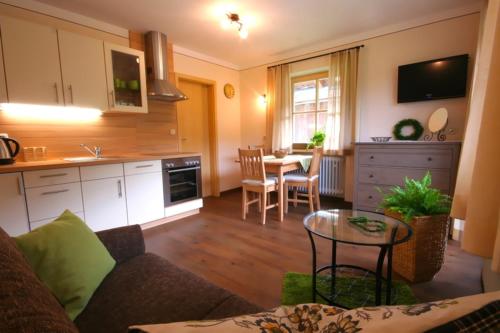 ein Wohnzimmer mit einem Sofa und einem Tisch in der Küche in der Unterkunft Staller Hof in Ruhpolding