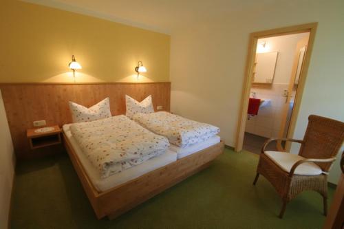 a bedroom with a large bed with a chair and a table at Staller Hof in Ruhpolding