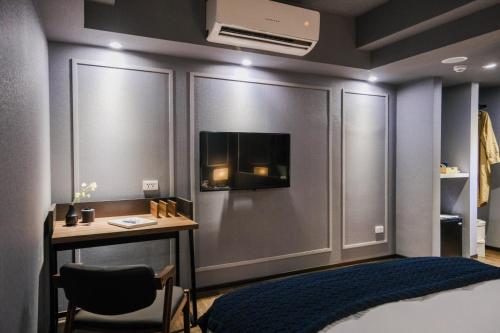 a bedroom with a bed and a desk and a tv on the wall at Giant Rich Hotel in Taipei