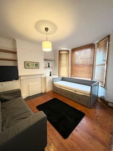 a living room with a bed and a couch at Spacious flat with patio garden in Raynes Park