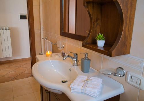 a bathroom with a sink with a mirror and a candle at Iris Apartment, Parco Velino Sirente in Celano
