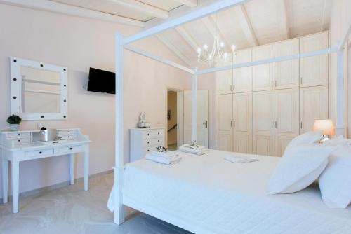 a white bedroom with a white bed and a desk at Villa Frosso in Kalami