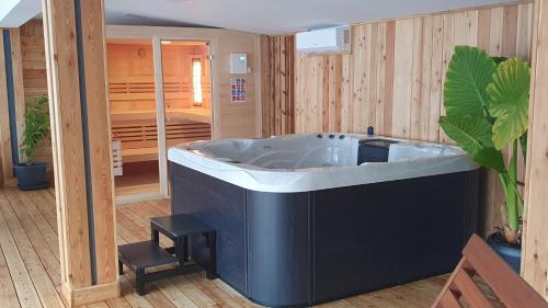 een groot bad in een kamer met houten wanden bij Apartments Akacijev Izvir in Miklavž na Dravskem Polju