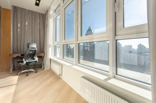 ein Büro mit einem Schreibtisch und einem Stuhl vor den Fenstern in der Unterkunft 16141 Jack House Panoramic city view in Kiew