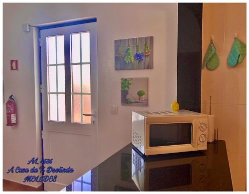 a microwave sitting on a table next to a door at A Casa da Ti Deolinda in Melides
