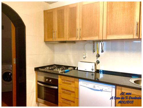 a kitchen with wooden cabinets and a stove top oven at A Casa da Ti Deolinda in Melides