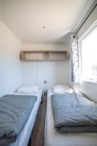 two beds in a room with a window at Camping du Sevron in Saint-Étienne-du-Bois