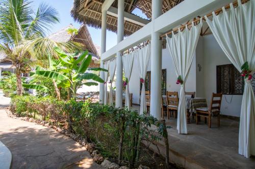 a dining room at a resort with white curtains at Rafiki Village in Watamu