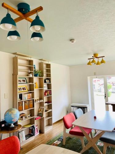 a living room with a table and chairs and bookshelves at HIROSAKI清水森はうす in Hirosaki