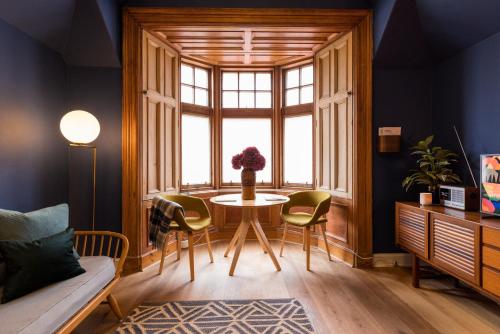 sala de estar con mesa, sillas y ventana en JOIVY Contemporary cottage with parking, en Edimburgo