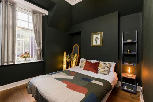 1 dormitorio con paredes verdes, 1 cama y ventana en JOIVY Contemporary cottage with parking, en Edimburgo