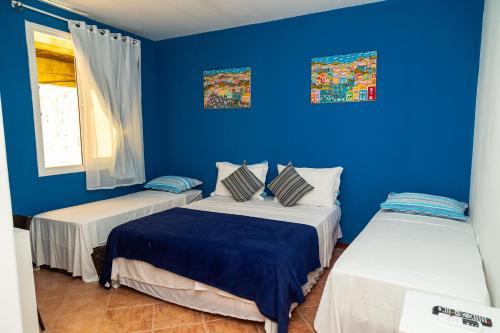 2 camas en una habitación con paredes azules en Pousada Michele, en Morro de São Paulo