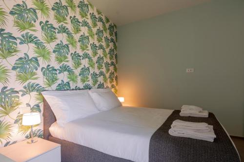 um quarto com uma cama com papel de parede tropical em AlbaResidence Vico01 em Alba