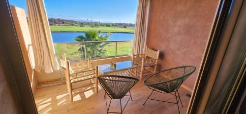 une chambre avec deux chaises et un balcon avec vue dans l'établissement Appt vue golf et atlas, à Marrakech