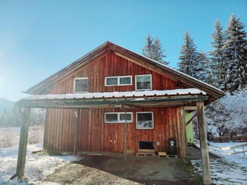 a red barn with snow on top of it at Haus Branol in Hermagor