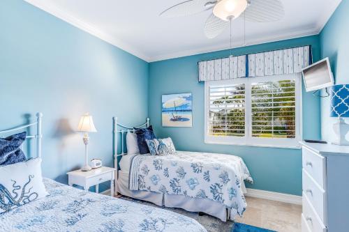 a blue bedroom with two beds and a window at Marco Paradise in Marco Island