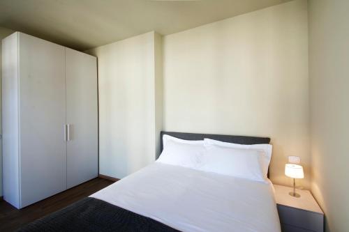 a bedroom with a white bed and a white closet at AlbaResidence Vico01 in Alba