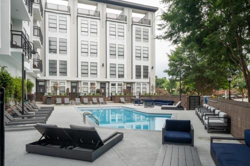 a swimming pool with lounge chairs and a building at Uptown Townhouse Studio Apartment -WiFi-10 min walk to Spectrum Center in Charlotte