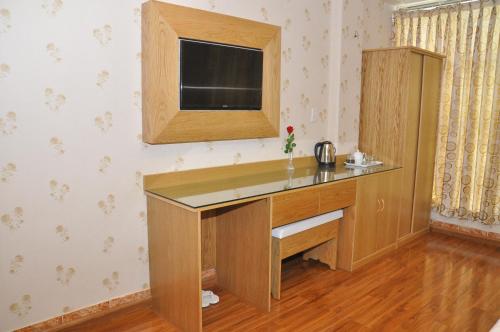 einen Schreibtisch in einem Zimmer mit einem TV an der Wand in der Unterkunft Phu Qui Hotel in Soc Trang