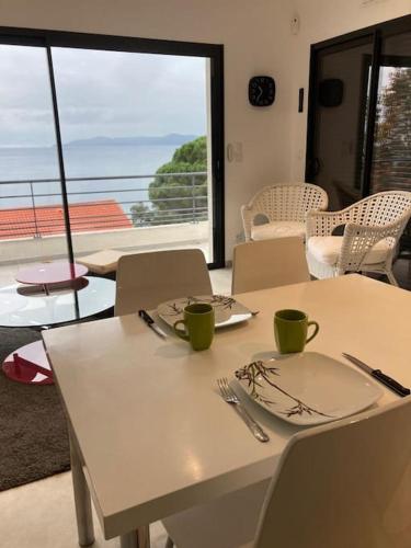 - une table blanche avec des assiettes et des ustensiles dans l'établissement Cap Sud,apt 4p,vue mer,pr plage, au Lavandou