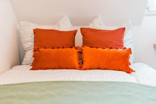a white bed with two orange pillows on it at Stuttgart am Wasen Toplage 4Zi 80qm in Stuttgart