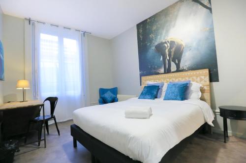 a bedroom with a large bed with a painting on the wall at La Jungle, T5 hypercentre chic et cosy, wifi, netflix par SOVALFI in Saint-Étienne