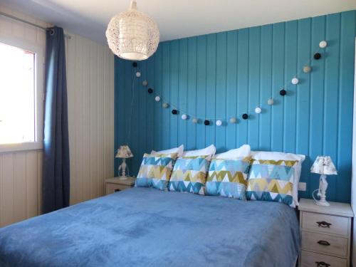 Un dormitorio con una cama con paredes azules y una lámpara de araña. en Gîte Meillard, 3 pièces, 4 personnes - FR-1-489-93, en Meillard