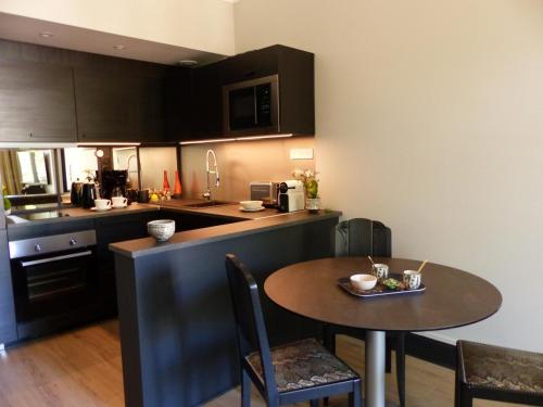 - une cuisine avec une petite table, une table et des chaises dans l'établissement Appartement élégant et confortable au cœur de Vichy, près de l'Opéra et des Parcs Napoleon III - FR-1-489-303, à Vichy