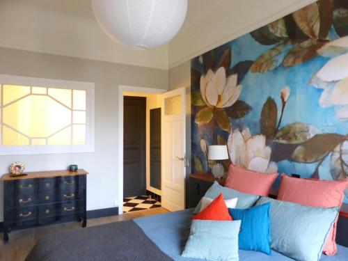 une chambre avec un canapé bleu et une fresque florale dans l'établissement Appartement élégant et confortable au cœur de Vichy, près de l'Opéra et des Parcs Napoleon III - FR-1-489-303, à Vichy