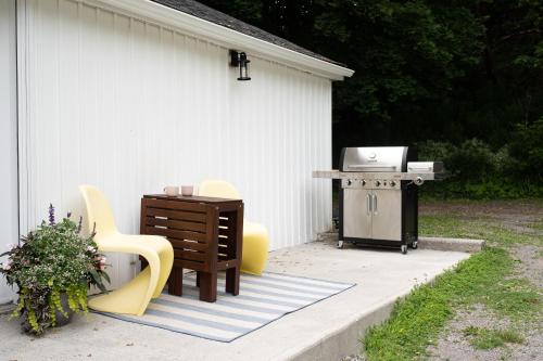a patio with chairs and a table and a grill at Downtown Picton 2-Bedroom Boho Suite! in Picton