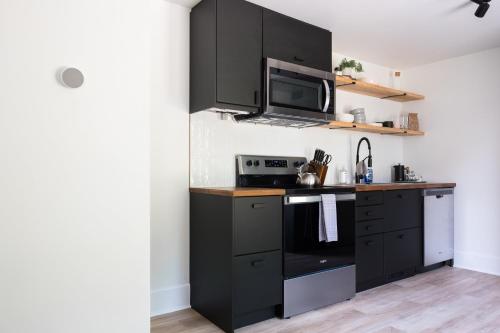 une cuisine avec des armoires noires et un four micro-ondes dans l'établissement Downtown Picton 2-Bedroom Boho Suite!, à Picton