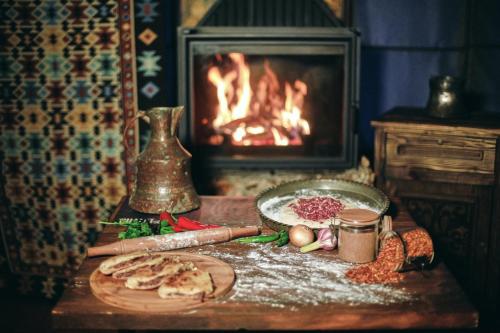 a table with a plate of food and a fireplace at Chalet Mestia in Mestia