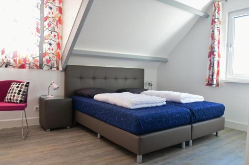 a bedroom with a bed and a red chair at Woning zeldenrust 4 in Oostkapelle