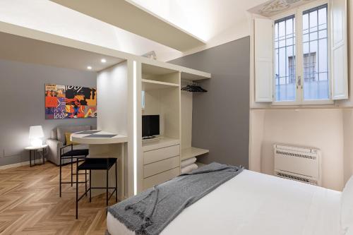 a bedroom with a bed and a desk with a tv at Palazzo Liberati Apartments in Parma